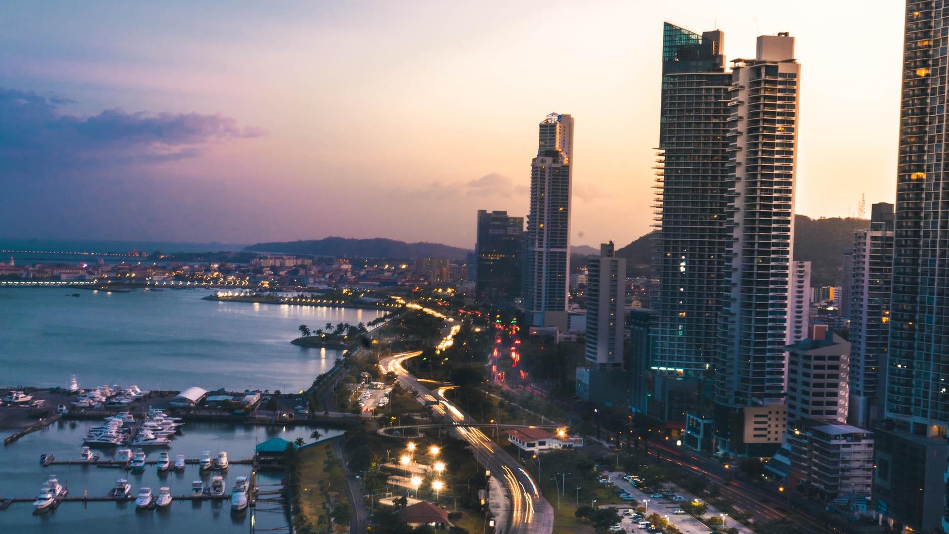 high rise buildings near body of water in distant of mountain